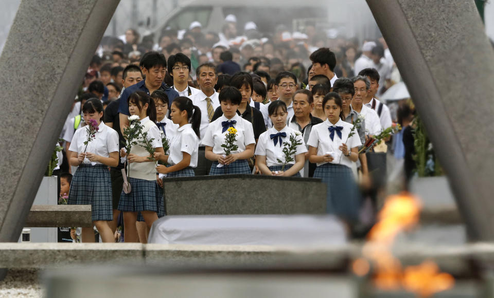 People pray for the atomic bomb victims in front of the cenotaph at the Hiroshima Peace Memorial Park in Hiroshima, western Japan during a ceremony to mark the 74th anniversary of the bombing Tuesday, Aug. 6, 2019. (Kyodo News via AP)