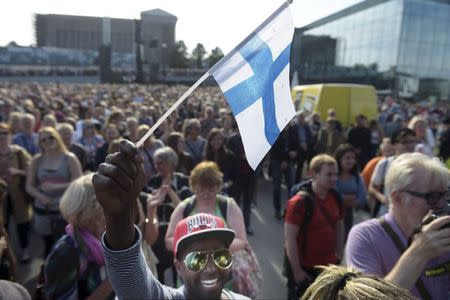 Mire Ibrahim waves the Finnish flag during a demonstration against racism where an estimated 15,000 people attended in Helsinki, Finland on July 28th, 2015. REUTERS/Vesa Moilanen/Lehtikuva
