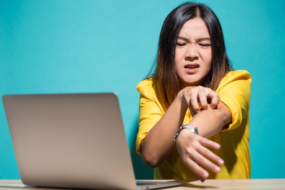 A frustrated woman scratches at her arm