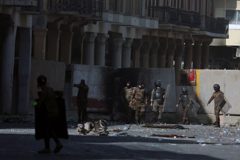 Riot policemen react during the ongoing anti-government protests in Baghdad