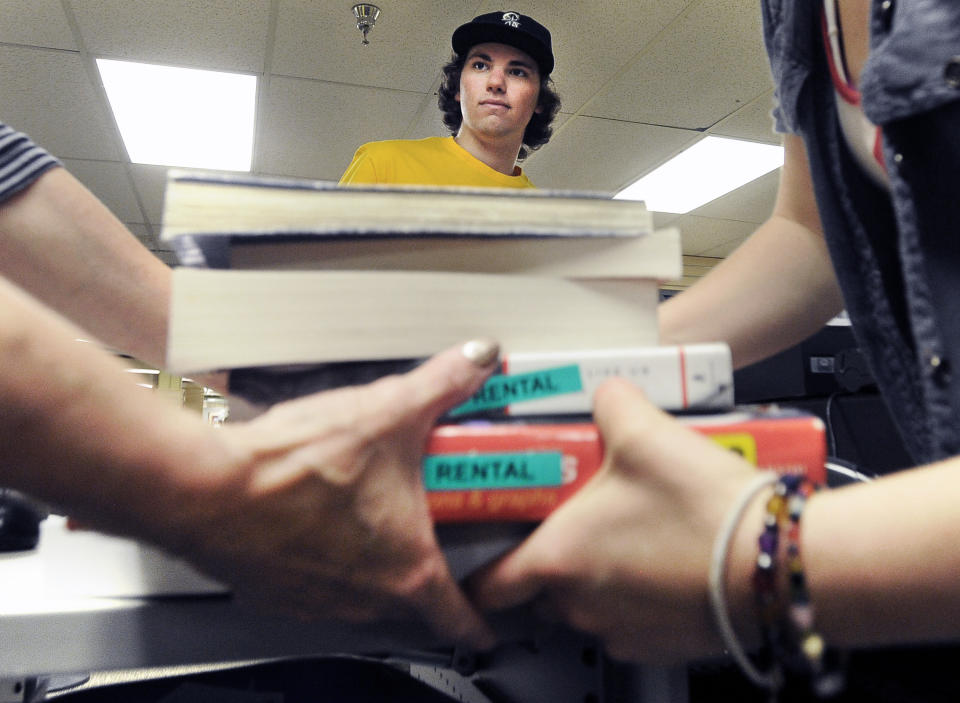 University of Colorado sophomore Evan Michalec watches as employees Kerrie Summerhays, left, and Justice Cook carry away his textbooks after selling them back to the CU bookstore inside on Friday, May 10, at the University Memorial Centeron the CU campus in Boulder.(Photo by Jeremy Papasso/Digital First Media/Boulder Daily Camera via Getty Images)