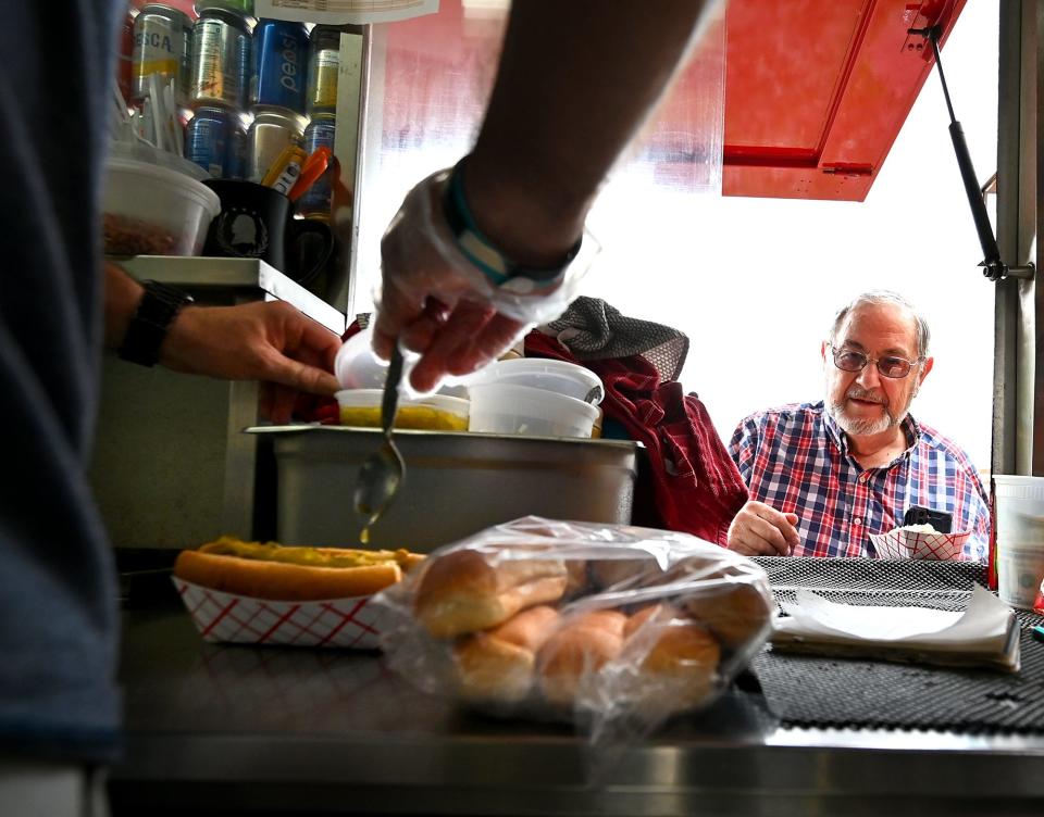 GRAFTON - Ed Leonard of Grafton watches as Best in Show Hot Dogs owner Justin Wnukowski adds relish to his hot dog on Wednesday. Ed got the two dog special and his wife, Noni, enjoyed the Schnauzer, which is warm kraut and spicy mustard.