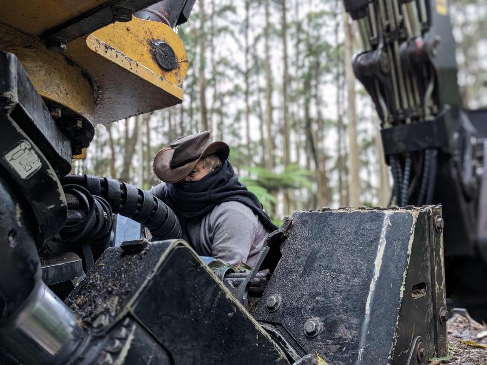 A protester, face covered, locked onto equipment.