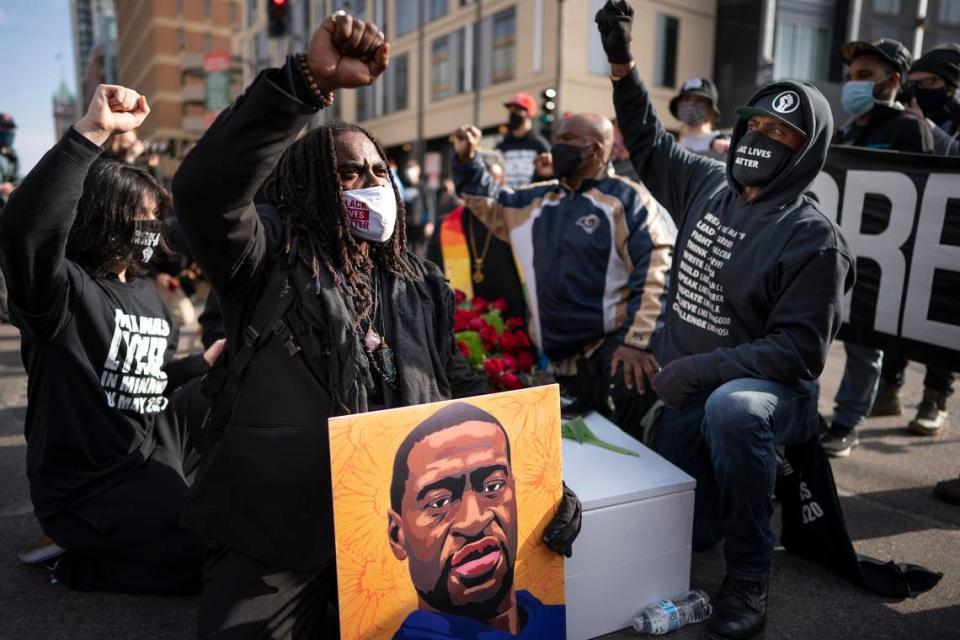 Cortez Rice, left, of Minneapolis, sits with others in the middle of Hennepin Avenue on Sunday, March 7, 2021, in Minneapolis, Minn., to mourn the death of George Floyd a day before jury selection is set to begin in the trial of former Minneapolis officer Derek Chauvin, who is charged in Floyd’s death. (Jerry Holt/Star Tribune via AP)