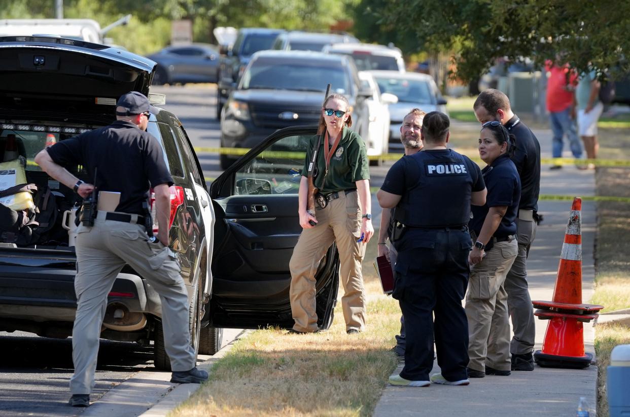 An investigator takes a gun from the scene of a police shooting on Channel Island Drive in South Austin on Monday. An officer was wounded and the shooter was also injured in the incident Sunday night, Police Chief Joe Chacon said.