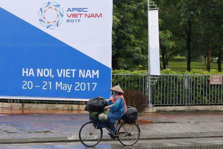 A woman bikes past a banner welcoming APEC trade ministers for a meeting in Hanoi, Vietnam May 19, 2017. REUTERS/Kham