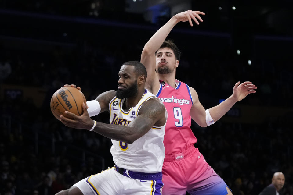 Los Angeles Lakers' LeBron James, left, gets a rebound against Washington Wizards' Deni Avdija (9) during first half of an NBA basketball game Sunday, Dec. 18, 2022, in Los Angeles. (AP Photo/Jae C. Hong)