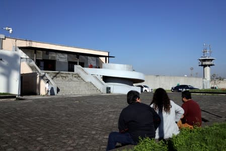 People sit near the entrance to Santa Martha Acatitla prison, where former social development minister Rosario Robles was taken into custody, in Mexico City