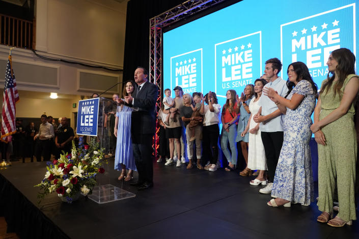 Sen. Mike Lee, R-Utah, and his wife, Sharon Lee, backed on stage by family members, talk to supporters during a Republican primary-night party Tuesday, June 28, 2022, in South Jordan, Utah. (AP Photo/George Frey)