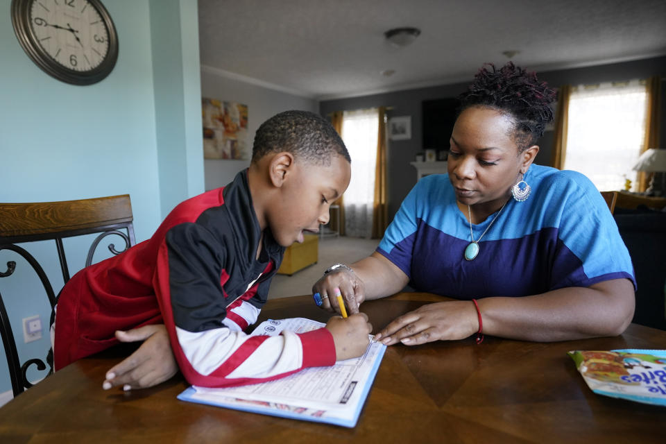 Tamela Ensrud helps her son, Christian, 7, with his homework at their home Monday, Nov. 21, 2022, in Nashville, Tenn. As parents try to help their children recover from nearly three years of interrupted learning, some are struggling to get clear information explaining how their children are performing or a school plan to help them catch up on the learning they missed. (AP Photo/Mark Humphrey)