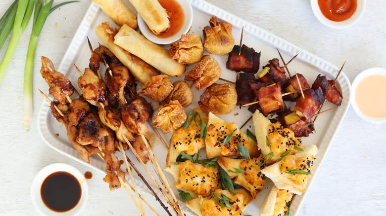 pu pu platter on serving tray next to sauces