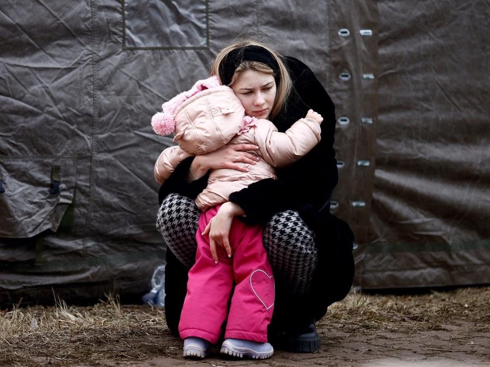 A woman fleeing Russian invasion of Ukraine hugs a child at a temporary camp in Przemysl, Poland, February 28, 2022