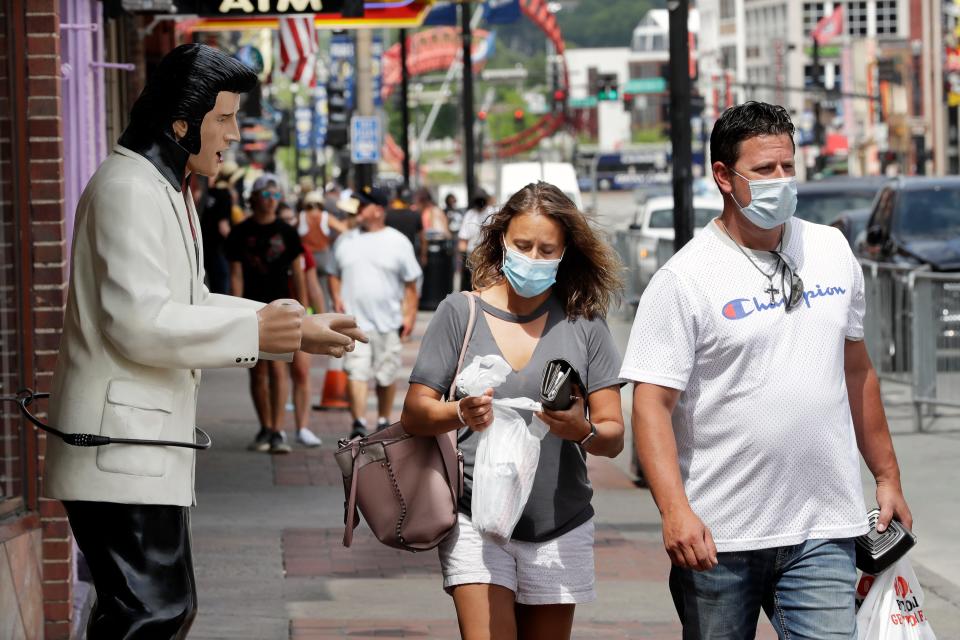 People wear masks as they walk by a statue of Elvis Presley Tuesday, June 30, 2020, in Nashville, Tenn. The Nashville Health Department has put in place a mask mandate to help battle the spread of the coronavirus.