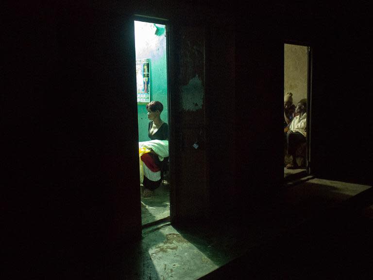 Fishermen drink at a bar as a sex-worker waits for clients at Kasensero on the shores of the Lake Victoria in Uganda on February 20, 2014