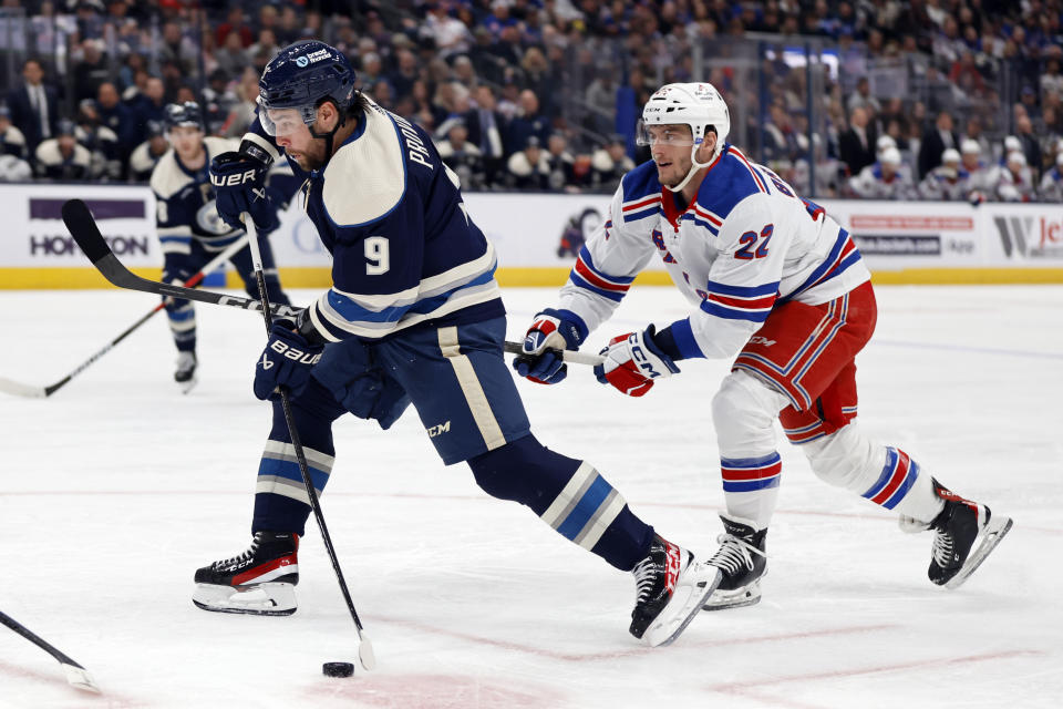 Columbus Blue Jackets defenseman Ivan Provorov, left, shoots the puck in front of New York Rangers forward Jonny Brodzinski, right, during the second period of an NHL hockey game in Columbus, Ohio, Sunday, Feb. 25, 2024. (AP Photo/Paul Vernon)