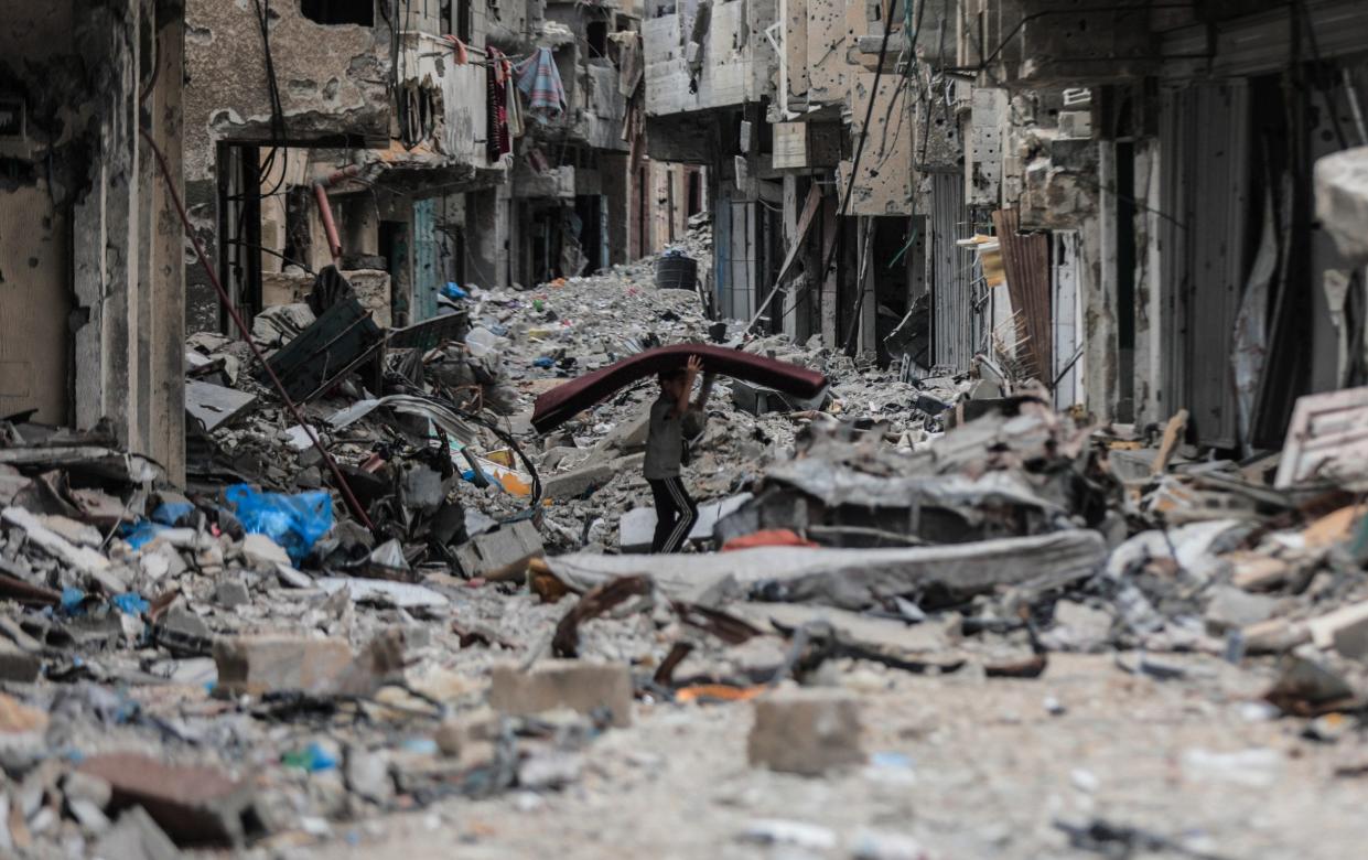 A Palestinian child carries usable items among buildings, some of which are destroyed and the majority of which are heavily damaged and unusable as Palestinians who returned to the city of Khan Yunis in the south of Gaza