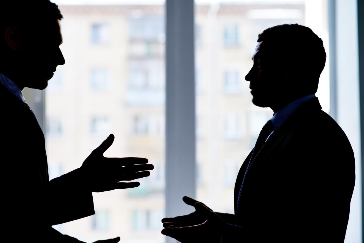 Back lit image of two businessmen arguing