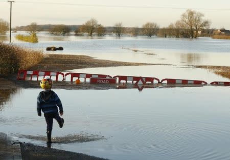 A boy stands next to the road to Cawood which is completely submerged under flood waters in northern England, December 27, 2015. REUTERS/Andrew Yates