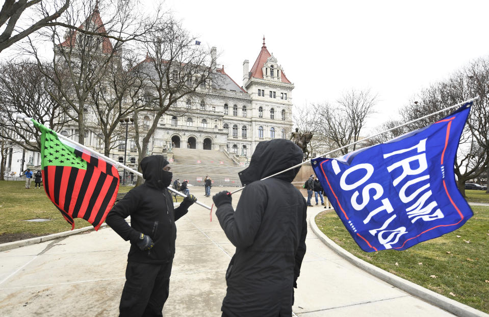 A supporter from Black Liberation left, and one from the group "All Of Us' hold flags while counter-protesting a Trump rally ahead of the inauguration of President-elect Joe Biden and Vice President-elect Kamala Harris at the New York State Capitol Sunday, Jan. 17, 2021, in Albany, N.Y. (AP Photo/Hans Pennink)