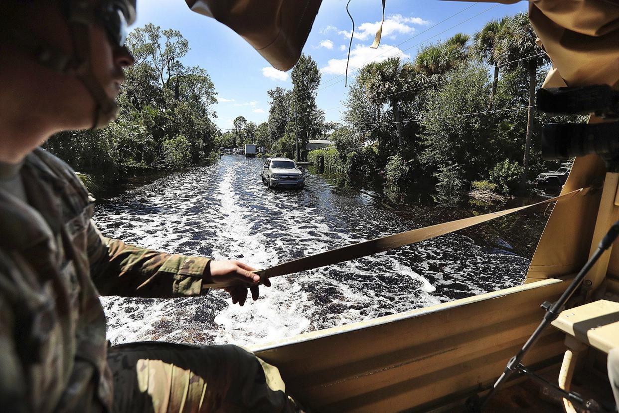 Members of the National Guard ride in a rescue truck down a flooded road in Geneva, Fla., Saturday, Oct. 1, 2022. The area is heavily flooded after Hurricane Ian.