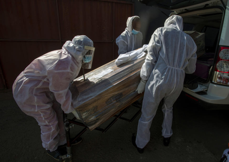 Funeral home workers in protective suits carry the coffin of a woman who died from COVID-19 into a hearse in Katlehong, near Johannesburg, South Africa, July 21 2020. (AP Photo/Themba Hadebe)