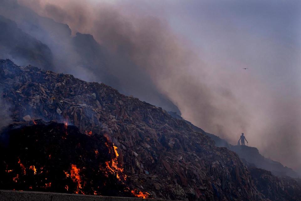 PHOTO: A person picks through trash for reusable items as a fire rages at the Bhalswa landfill in New Delhi, April 27, 2022. (Manish Swarup/AP)