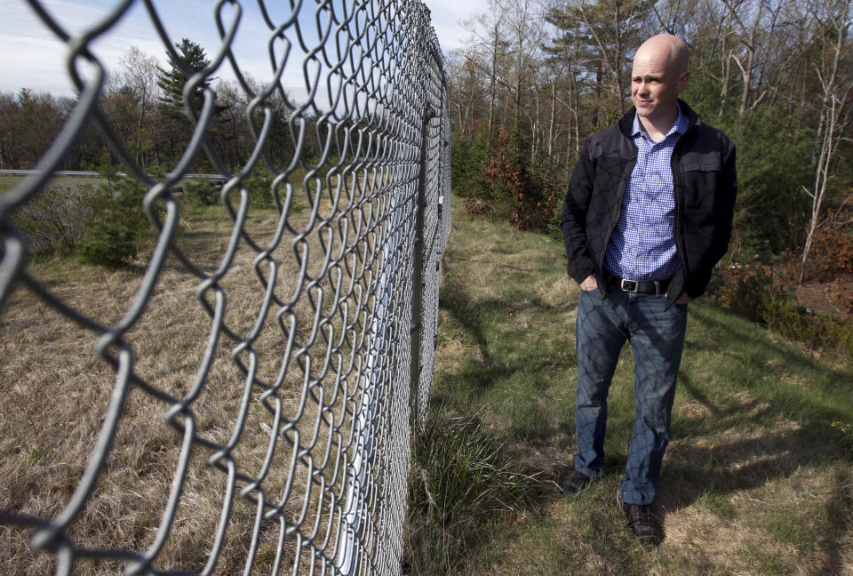 In this April 19, 2012, photo, Mike McCarthy, of Walpole, Mass., walks near a chain link fence in Foxborough, Mass., that runs along the edge a parking lot that could become the site of a proposed gambling casino. McCarthy's property in Walpole, and the Walpole town line, are about 15 feet from the fence, and McCarthy, who has two young children, worries about the impact a casino would have so close to his home. (AP Photo/Steven Senne)