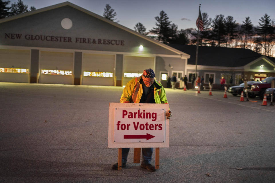 Roy McPhail sets up a sign shortly before the doors opened to voters at 6:00 A.M. at the fire station, Tuesday, Nov. 8, 2022, in New Gloucester, Maine. (AP Photo/Robert F. Bukaty)