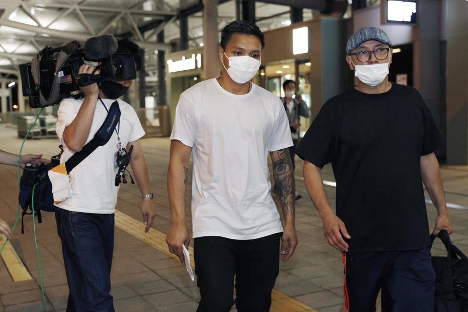 Pyae Lyan Aung, center, a substitute goalkeeper of the Myanmar national team who raised a three-finger salute during a qualifying match for the 2022 World Cup in late May, arrives at Kansai International Airport in Osaka Prefecture, Japan on Thursday June 17, 2021. Pyae Lyan Aung has refused to return home and is seeking asylum, a request the government was considering taking into account unrest in his country following a coup.(Kyodo News via AP)