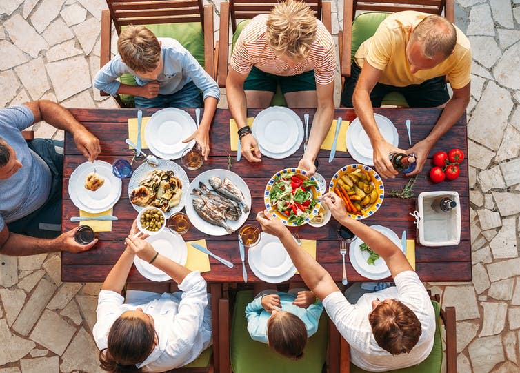 A family sitting around a dinner table eating.