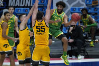 Oregon guard LJ Figueroa (12) passes around Iowa center Luka Garza (55) during the second half of a men's college basketball game in the second round of the NCAA tournament at Bankers Life Fieldhouse in Indianapolis, Monday, March 22, 2021. (AP Photo/Paul Sancya)