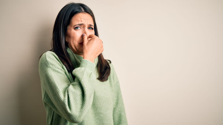 woman holding nose