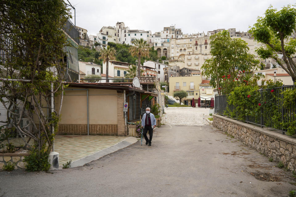 In this picture taken on Tuesday, April 28, 2020, a man walks in a deserted street in the seaside town of Sperlonga, about 120km (80 miles) south of Rome. Normally, at this time of year Sperlonga would already be bustling with its first clients of the season. The restaurants would be fully operational and the golden-sand beaches, although still too chilly for Italians, would have been enjoyed by northern Europeans eager for some sunlight after a long, dark winter. (AP Photo/Andrew Medichini)