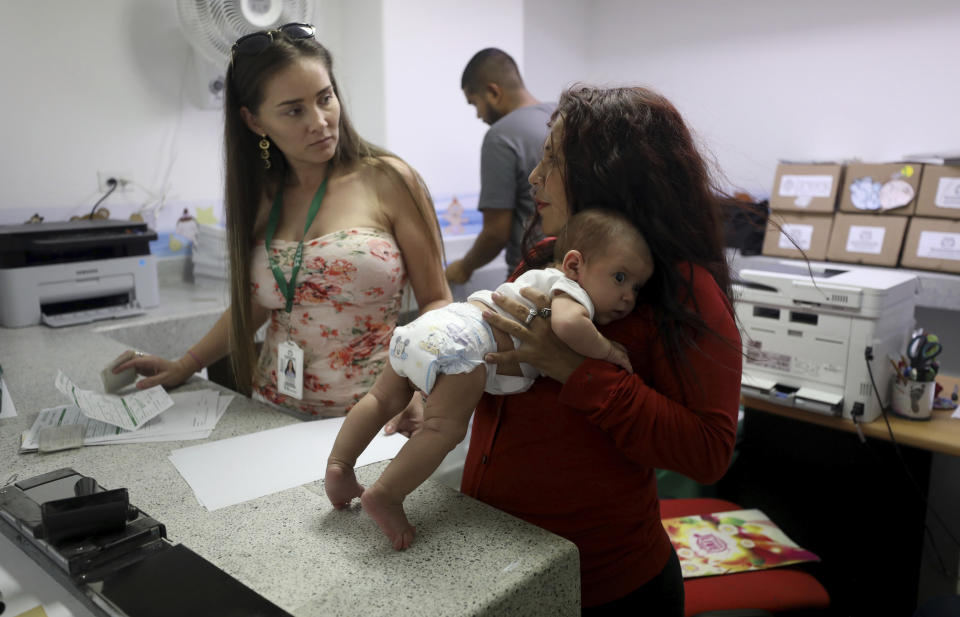 Arelys Pulido, a la derecha, sostiene a su hija de dos meses Zuleidys Antonella Primera mientras hace los trámites para el certificado de nacimiento del bebé en el hospital Erazmo Meoz en Cúcuta, Colombia, en la frontera con Venezuela, el jueves 2 de mayo de 2019. (AP Foto/Fernando Vergara)