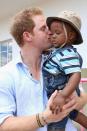 <p>Harry kisses a toddler on the cheek on a charity visit in 2014.</p>