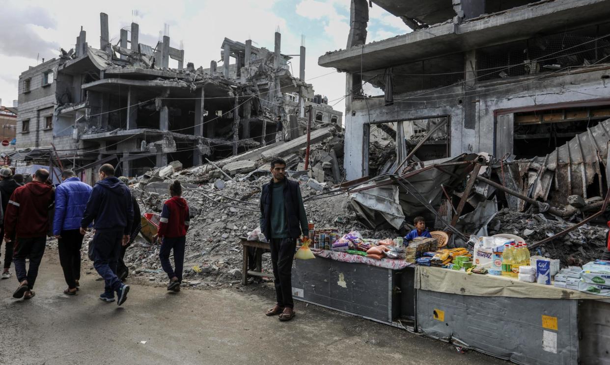 <span>Palestinians walk past destroyed buildings in Rafah as a stall sells a small amount of provisions.</span><span>Photograph: Anadolu/Getty Images</span>