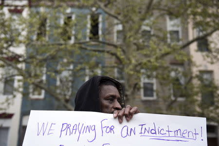 A demonstrator holds a sign in front of the Baltimore Police Department Western District station to protest against the death in police custody of Freddie Gray in Baltimore April 23, 2015. REUTERS/Sait Serkan Gurbuz