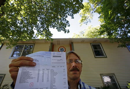 Dan Koivisto poses with a copy of his 2013 property tax bill at his home in Ingleside, Illinois, United States, July 30, 2015. REUTERS/Jim Young