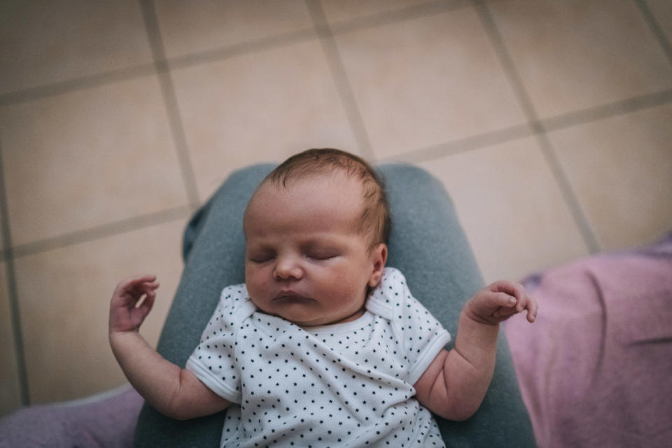 Baby sleeping on parent's lap in onesie