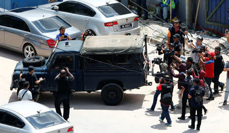 Journalists chase a police vehicle transporting the body of a landslide victim at a construction site in Tanjung Bungah, a suburb of George Town, Penang, Malaysia October 22, 2017. REUTERS/Lai Seng Sin