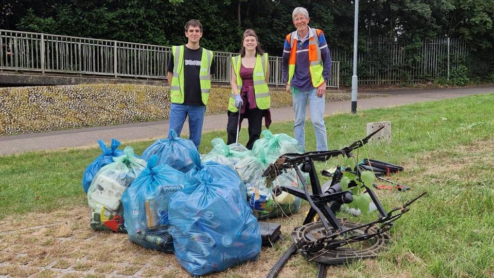 Litter picking volunteers pose in front of collected rubbish bags 