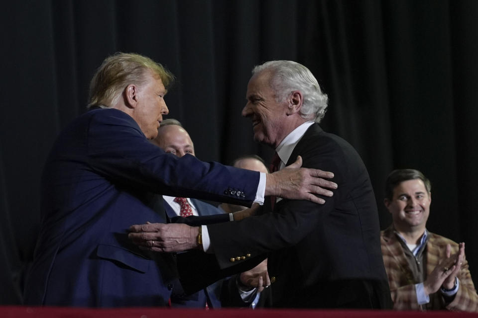 Republican presidential candidate former President Donald Trump, left, and South Carolina Gov Henry McMaster, right, embrace on stage during a campaign event in Manchester, N.H., Saturday, Jan. 20, 2024. Also on stage is South Carolina House Speaker Murrell Smith, far right. (AP Photo/Matt Rourke)