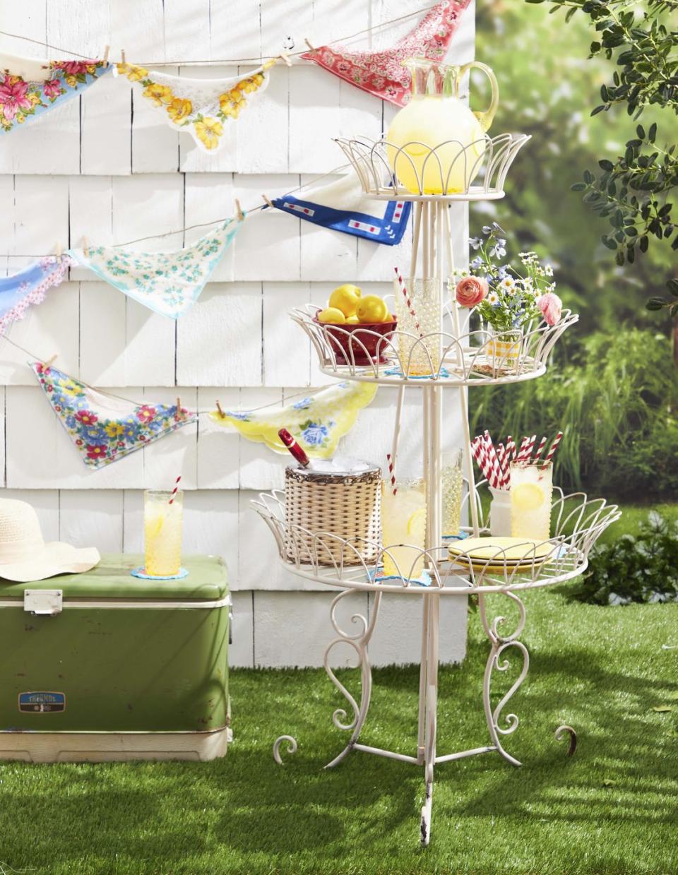 bunting made from vintage hankies hung on an outdoor wall with a tiered lemonade stand in front