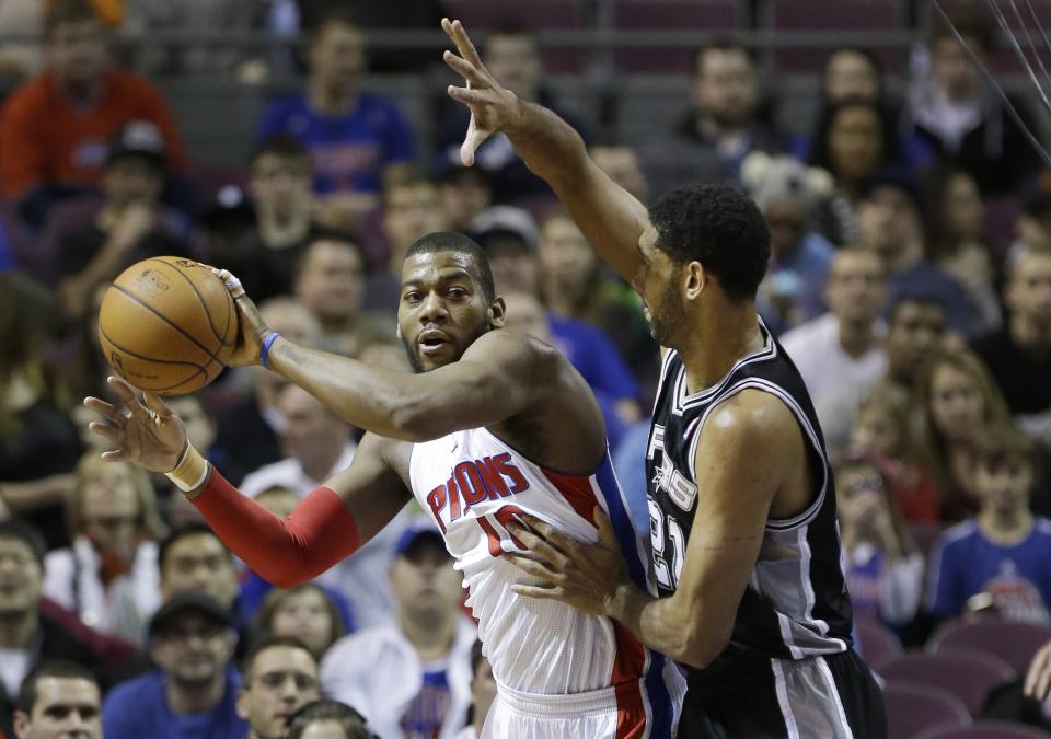 Detroit Pistons forward Greg Monroe (10) passes the ball as he is defended by San Antonio Spurs forward Tim Duncan (21) during the first half of an NBA basketball game in Auburn Hills, Mich., Monday, Feb. 10, 2014. (AP Photo/Carlos Osorio)