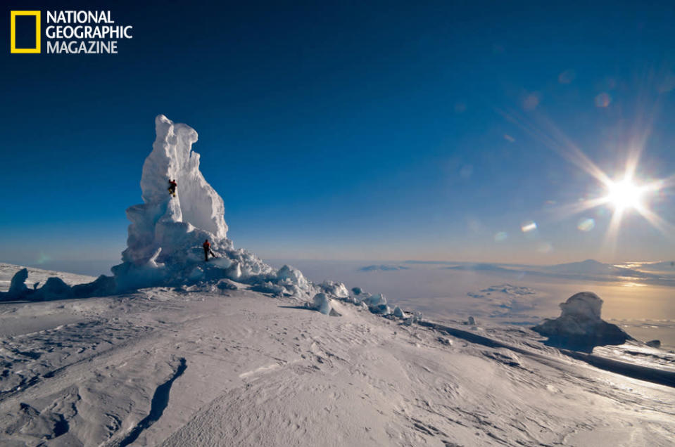 It's midnight, but with the light so bright, it's hard to stop exploring the ice towers. This is one of the biggest on Erebus, but the flux of heat and moisture from below has collapsed its side. In the distance, beyond another ice tower, the Hut Point Peninsula extends like a finger toward Mount Discovery. (photo © Carsten Peter/National Geographic)