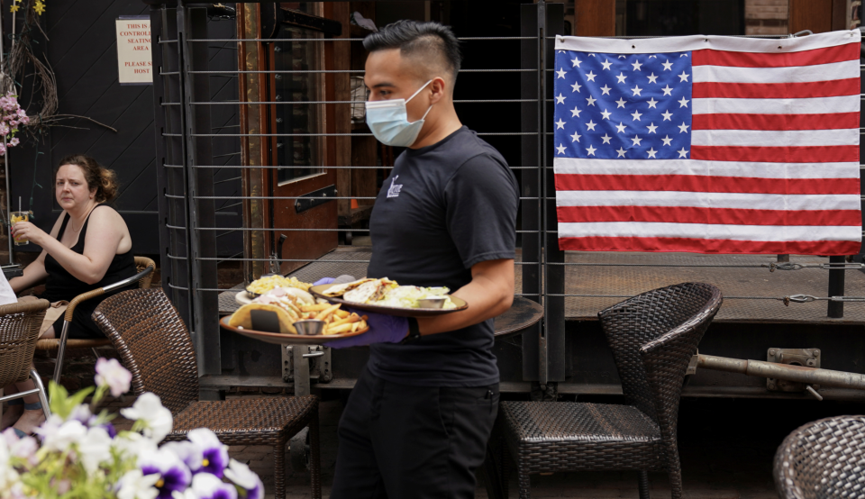 A waiter in a face mask to protect against the coronavirus (COVID-19) serves diners seated outdoors at a restaurant in Alexandria, Virginia, U.S., May 29, 2020.  (REUTERS/Kevin Lamarque)