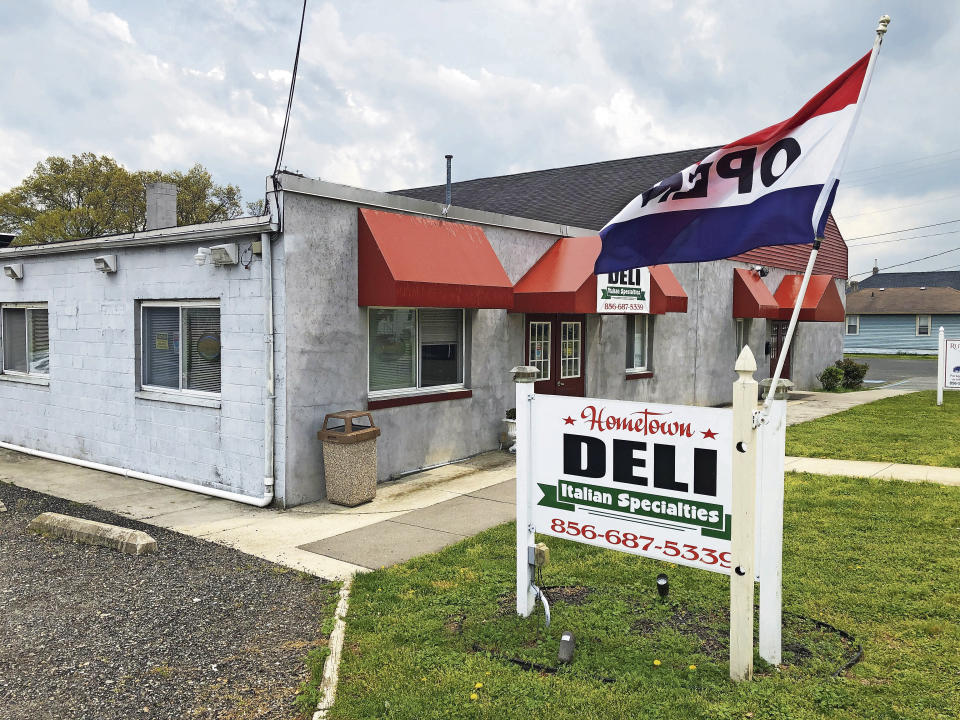 A flag waves over a sign outside the now-closed Hometown Deli, April 21, 2021 in Paulsboro, N.J. A suspect wanted in in connection with an alleged stock manipulation scheme famously involving the small New Jersey delicatessen has agreed to voluntary extradition to the United States after being arrested last week on the resort island of Phuket. (Peter Genovese, for The Star-Ledger via AP)