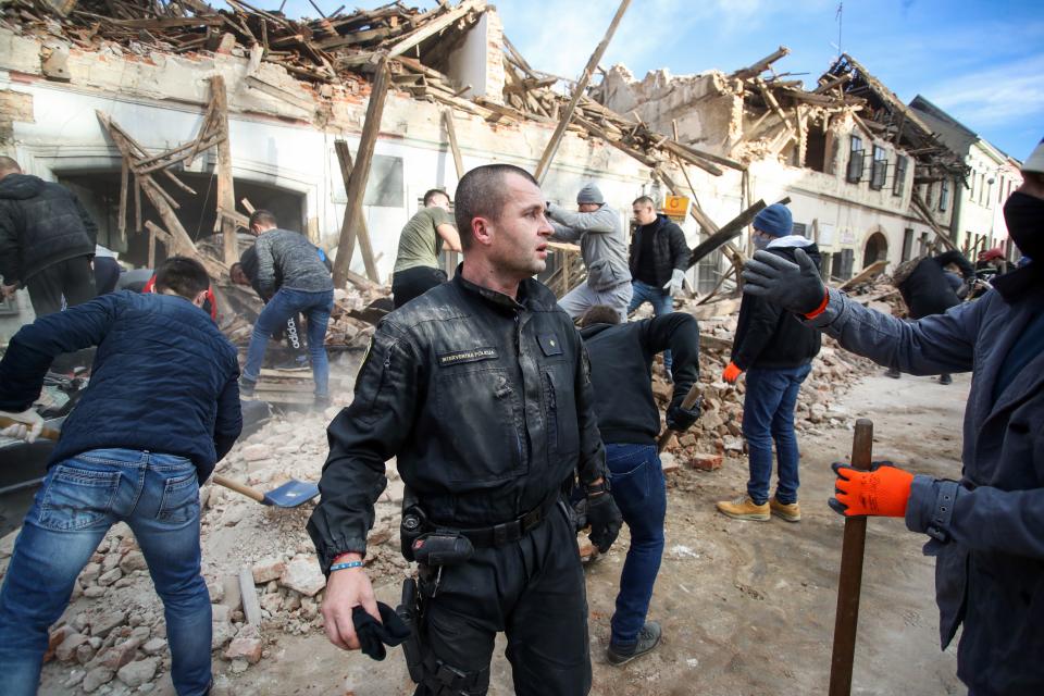 A member of Croatian Special Forces wearing a suit with dust takes a break from cleaning rubble from damaged buildings in Petrinja, some 50kms from Zagreb, after the town was hit by an earthquake of the magnitude of 6,4 on December 29, 2020. - The tremor, one of the strongest to rock Croatia in recent years, collapsed rooftops in Petrinja, home to some 20,000 people, and left the streets strewn with bricks and other debris. Rescue workers and the army were deployed to search for trapped residents, as a girl was reported dead. (Photo by Damir SENCAR / AFP) (Photo by DAMIR SENCAR/AFP via Getty Images)