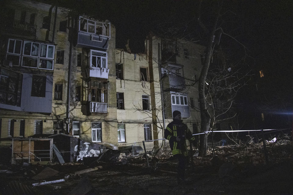 An emergency worker walks in front of a residential building which was hit by a Russian rocket in the city center of Kharkiv, Ukraine, Sunday, Jan. 29, 2023. (AP Photo/Yevhen Titov)