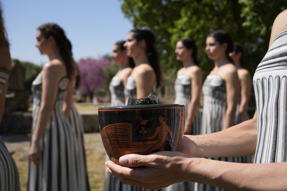 Una de las participantes en la ceremonia de encendido de la llama olímpica sostiene una vasija de cerámica que se utilizará en la ceremonia del martes, durante uno de los ensayos el domingo 14 de abril del 2024. (AP Foto/Thanassis Stavrakis)